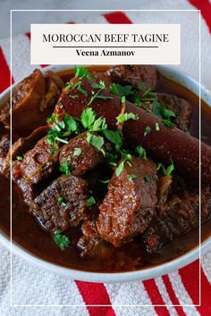 a bowl filled with meat and garnish on top of a red and white table cloth