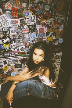 a woman sitting in front of a wall covered with stickers