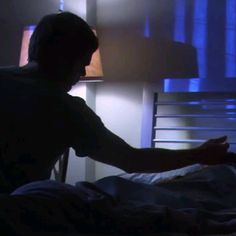 a man sitting in bed with his hand on the pillow