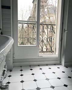 a bath tub sitting next to a window with a view of the eiffel tower