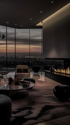a living room filled with furniture and a fire place in front of large windows at night