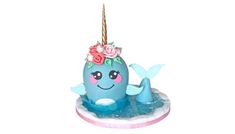 a birthday cake with a blue whale and flowers on it's head, sitting in the water