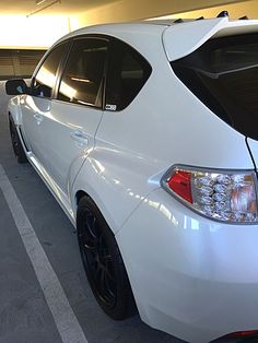 the back end of a white car parked in a parking garage