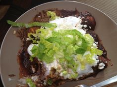 a white plate topped with meat covered in lettuce and cheese next to a fork