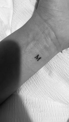 a small wrist tattoo with the letter n on it