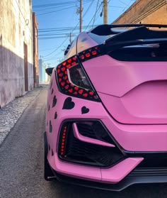 the rear end of a pink car with hearts painted on it