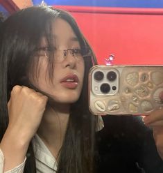 a woman taking a selfie with her cell phone in front of her face and wearing glasses