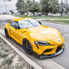 the yellow sports car is parked on the side of the road