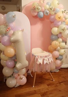 a chair and balloon arch for a first birthday party