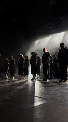 a group of people standing in the middle of a room with spotlights on them
