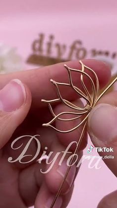a person holding a piece of metal with a flower on it's back end