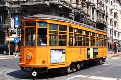 an orange trolley car traveling down a city street