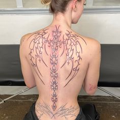 a woman sitting on the ground with her back tattoo