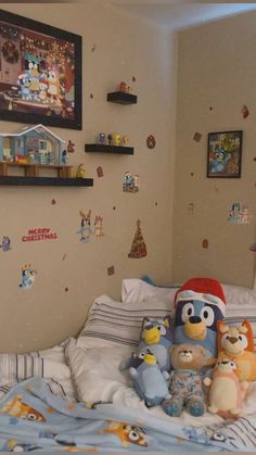 a bed with stuffed animals on top of it in front of a christmas themed wall