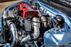 the engine compartment of a blue car with its hood up and it's intake exposed