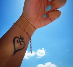 a woman's arm with a heart tattoo on it and a chain around the wrist