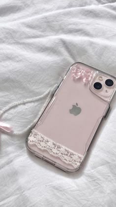 an iphone case laying on top of a white sheet with a pink ribbon attached to it