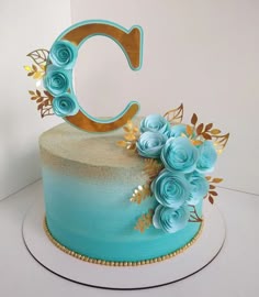 there is a cake with blue frosting and gold decorations on the top that says c