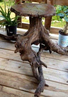 an old tree stump turned into a table on a deck with succulents and potted plants