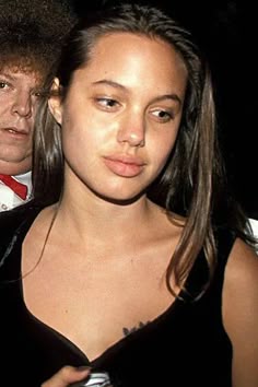 two people standing next to each other in front of a man with an afro on his head