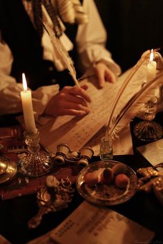 a person sitting at a table with an open book and quill in front of them