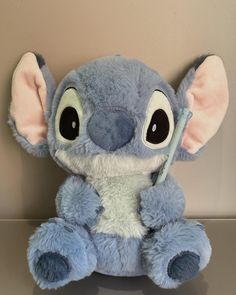 a blue stuffed animal sitting on top of a table next to a wall with an eye patch