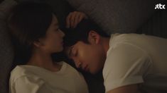 a man and woman laying on top of a couch next to each other with their eyes closed