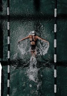 a woman swimming in the water wearing a white hat and black swim suit with no shirt on