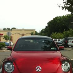 a red vw beetle parked in a parking lot