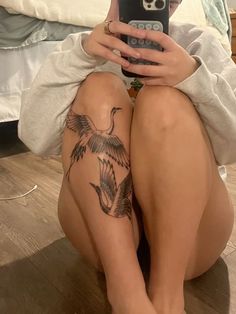 a woman is sitting on the floor with her legs crossed and holding a cell phone