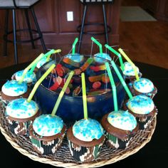 cupcakes and candy are arranged on a cake platter in the shape of a bowl