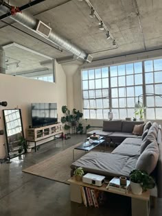 a living room filled with lots of furniture next to large windows and a flat screen tv on top of a wooden table