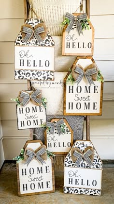 several wooden signs with bows on them sitting in front of a house and the words hello, home sweet home