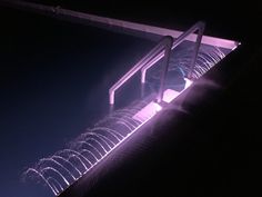 fireworks are lit up in the night sky behind a metal guard rail on top of a building