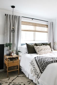 a bedroom with white bedding, black and white decor, and a wooden side table