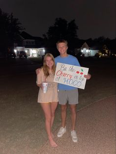 a man and woman standing next to each other holding a sign that says, do the cherry all at once