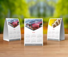 three calendars with cars on them sitting on a table in front of a blurry background