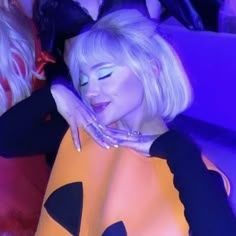 a woman with white hair and blue eyes posing for the camera in front of other women