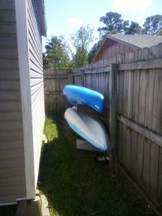 a blue and white surfboard leaning against a wooden fence