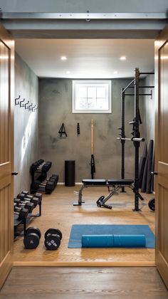 a home gym is shown with equipment in the doorway and on the floor, there are two rows of dumbbells