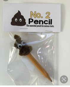 a pencil with a poop on it sitting in a package next to a stick