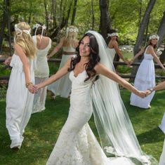 a woman in a wedding dress holding hands with other women wearing white dresses and veils