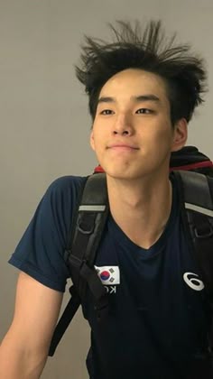 a young man with black hair wearing a backpack