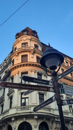 a street sign in front of a building with many signs on it's corner