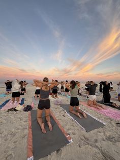 a group of people doing yoga on the beach
