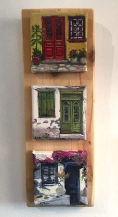 three paintings are hanging on the wall in front of a door and window with flowers