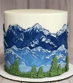 a cake decorated with mountains and trees on a plate