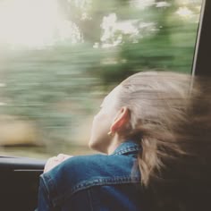 a woman is looking out the window of a car