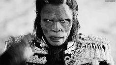 an old photo of a man with long hair and no face holding his hand up