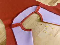 a piece of fabric is laying on the floor next to some sewing needles and thread